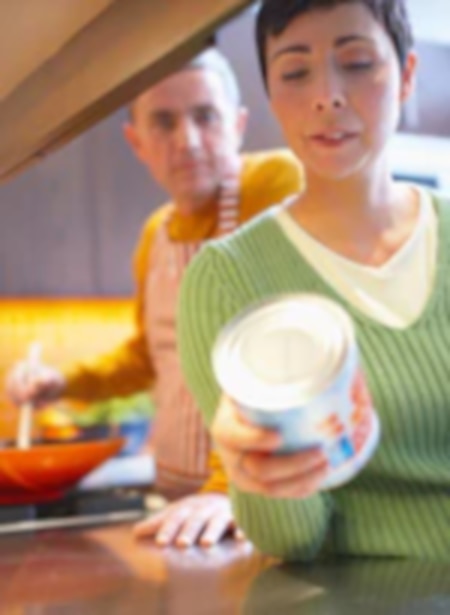 Woman inspecting canned food in kitchen