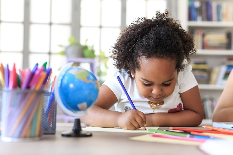 A young girl is coloring at a table.