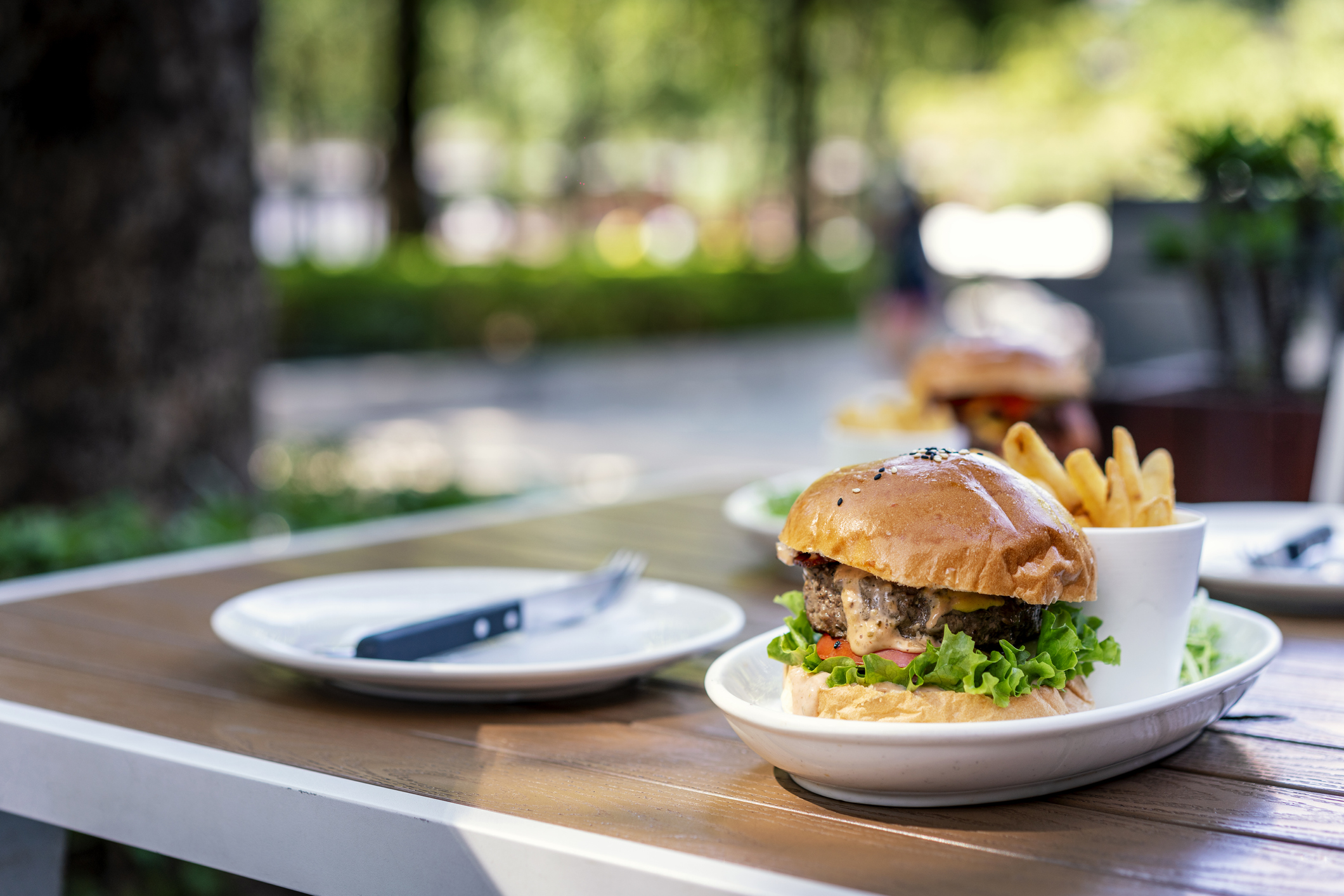 Una hamburguesa y papas fritas en una mesa de restaurante al aire libre.