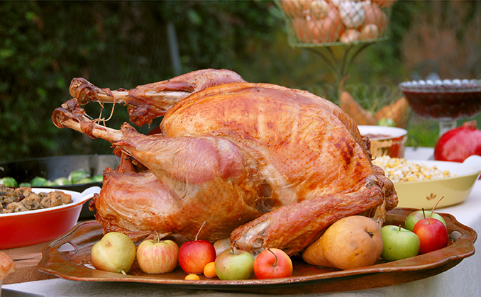 Roasted turkey on a platter with apples and pears.