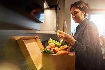 Mujer abriendo una caja con un kit de alimentos