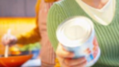 Woman inspecting canned food in kitchen