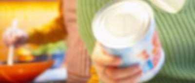 Woman inspecting canned food in kitchen