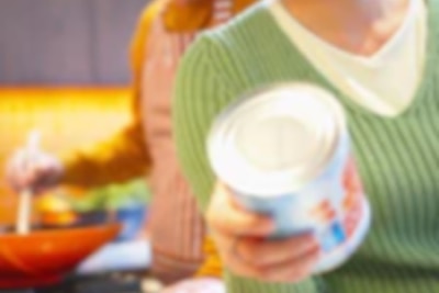 Woman inspecting canned food in kitchen