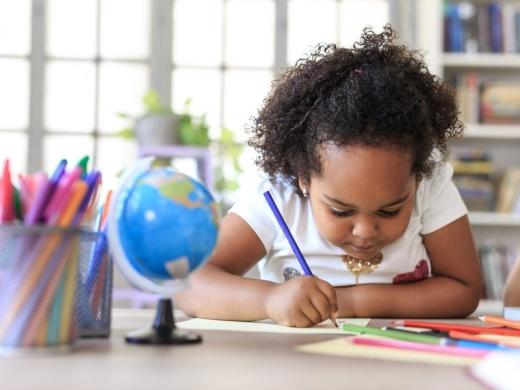 A young girl is coloring at a table.