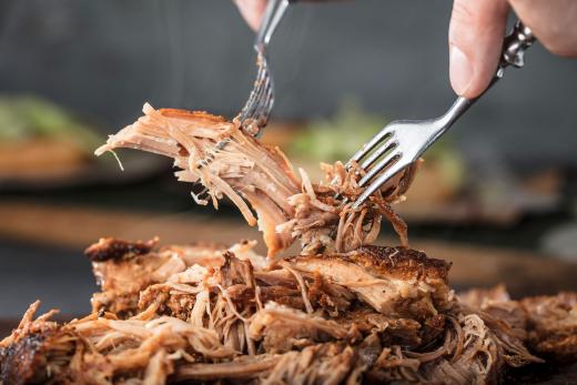 A forkful of slow-roasted pork over a platter of pork.
