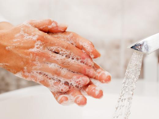 A person washing their hands with soap and water in a sink.